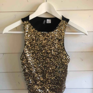  - En crop top från H&M med en guldglittrande framsida, kort i modellen. Köparen står för frakten!