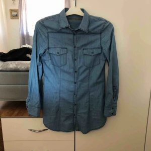  - Lång tun jeans skjorta, topp knappen saknas. Frakt tillkommer