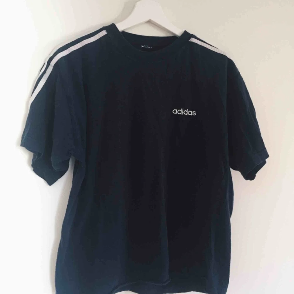 Oversized Adidas t-shirt, mörkblå med vita detaljer, köpt vintage. Bra skick, avklippta nedtill av förra ägaren. Passar som XS-M. Säljer för 50kr + eventuell frakt. . Skjortor.