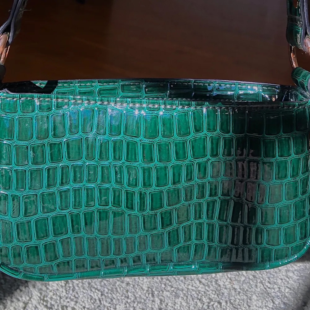 Liten grön väska i fake ”ormskinn”. Väldigt fin och bra skick men använder aldrig🖤. Väskor.