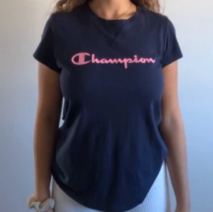 Champion t shirt - Den kostar 50kr utan frakt. Tröjan är stretchig och skön. Tröjan är mörk blå med rosa text. Den sitter fint och passar även M. Tröjan är lika bra som ny eftersom den är knappt använd. Tröjan sitter fint på alla kroppsformer. 💗✨