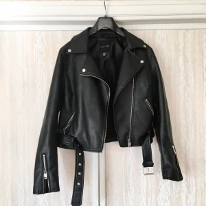 Skinnjacka/biker svart st 38 - En supersnygg skinnjacka i svart med silverdragkedja och knappar. St 38. I utmärkt skick! 50 cm längd.