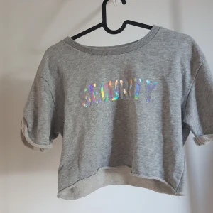 Crop top - Crop top i "mjukis" material från HM med tryck fram. Säljes då den aldrig används. Storlek XS (oversized). Passar också S-M (normalt). Frakt ingår.