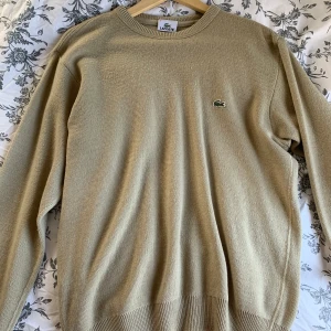 Stickad tröja - Beige stickad tröja med Lacoste märke vet ej om äkta💖köparen står för frakt eller så möts jag i Stockholm💖storlek M-L