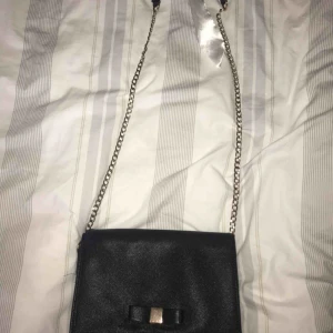  - Svart liten väska med rosett.