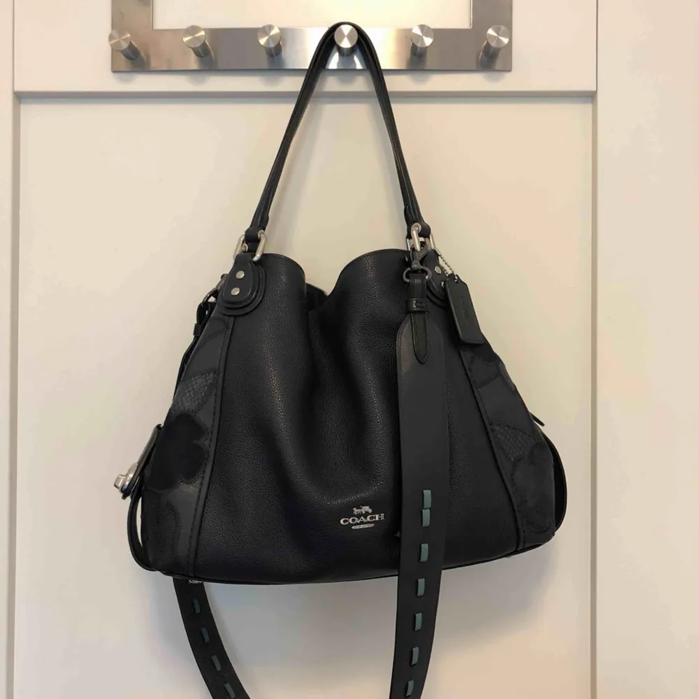 Edie shoulder bag från coach. Knappt använd och i mycket bra skick, säljer p.g.a används ej. Köpt i för 5500 kr inkl. bandet. Säljer för 2600. Stor och liten dustbag kommer med.  Höjd: 27 cm Längd 30 cm. Väskor.