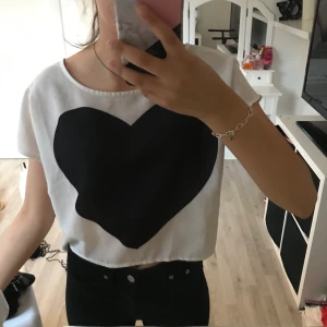  Blus  - En vit blus med ett svart hjärta och kappar bak, vid ryggen från H&M i storlek 36