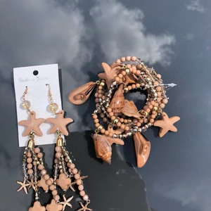 Armband örhängen set snäckor sjöfrukt - Vackra armband i bruna nyanser Örhängen i samma färg Armband 7 st kan separeras Med sjöfrukt -dekoration (3 st) övriga utan Guldiga och genomskinliga pärlor bland bruna. Aldrig använda. Kan skickas spårbart