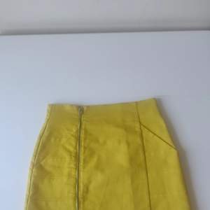 Kort tight solgul kjol från HM i lite 60-tals modell. Dragkedja och fickor samt detaljer på sidorna. Fint skick, inga anmärkningar. Kan skickas, jag står för frakten.