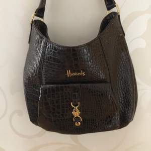 Glansig mörkbrun väska med gulddetaljer från Harrods💕  krokodilimitation! Knappt använd och bra skick