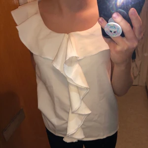 Fin vit topp - Väldigt unik, vit topp med volanger som min mamma har sytt. Har några år på nacken men är knappt använd. Jättefin till lite festligare tillfällen. Skulle säga att strl är XS/S. Skicka ett meddelande till mig om du vill ha fler/bättre bilder. 50kr+frakt ☺️