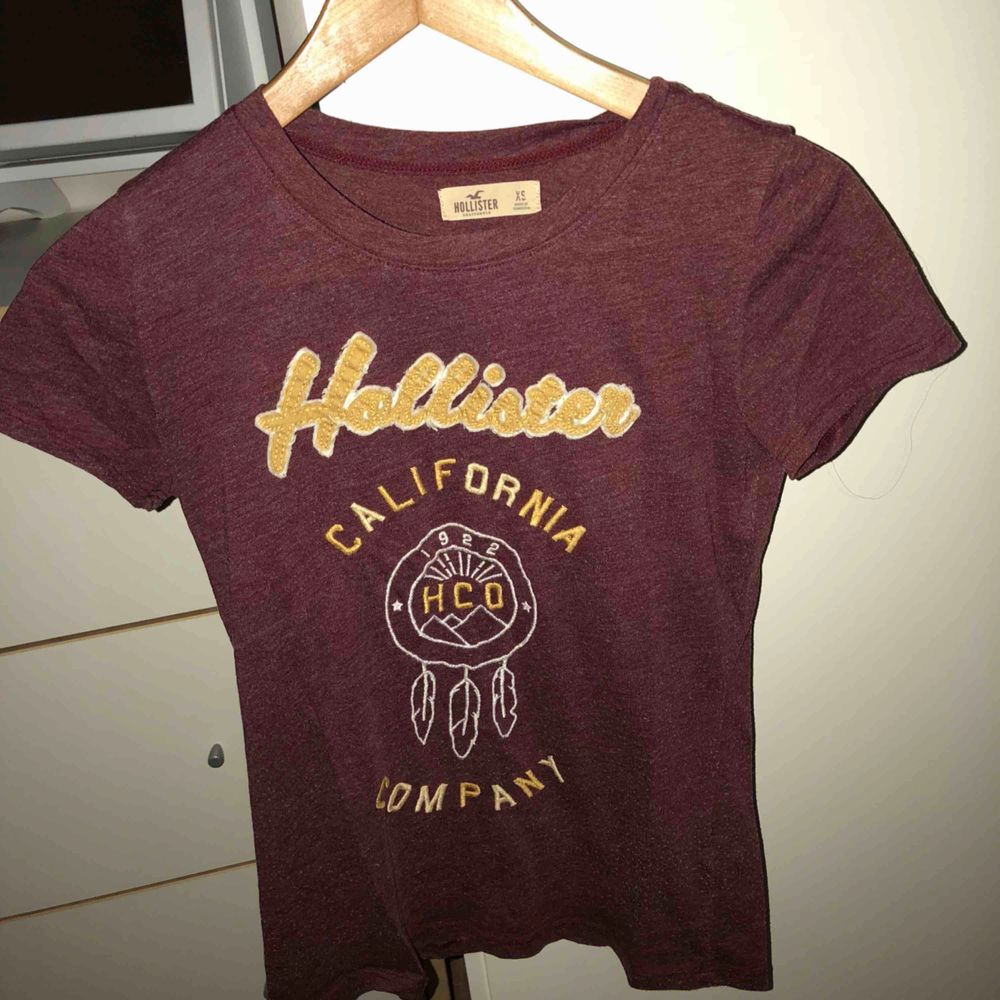 Vinröd Hollister t-shirt, ganska tight i passformen. (Kunden betalar frakten). T-shirts.