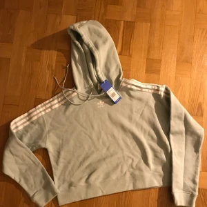  - Adidas chopped hoodie . Ljus blå eller ”dust green”