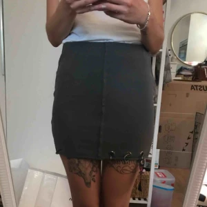  - Grå trikåkjol med metallringar