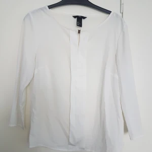 Vit blus S - Vit blus / topp med guldigt spänne. Står storlek 38 men motsvarar 36!! (alt. jätteliten 38a). Skönt silkigt material.