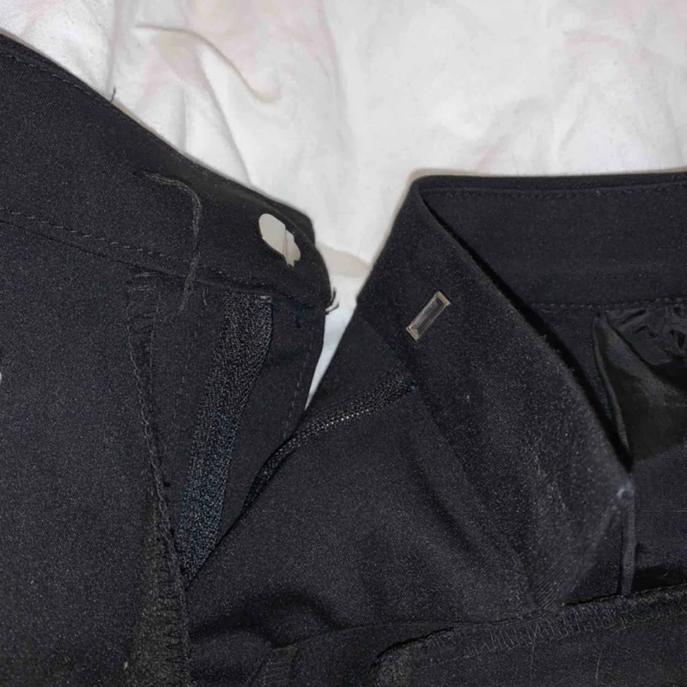 Svarta kostymbyxor med slits framtill. Perfekt för dig som är runt 160cm eller kortare. Knappen har lossnat (därav priset) men det går fortfarande att knäppa perfekt med kroken, enkelt att lösa genom att sy fast en ny knapp också. (Se bild 3)💞. Jeans & Byxor.