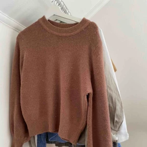  - Trendig stickad tröja med ballongärmar och i färgen brun. Den är lite nopprig, därav priset. Man kan dock "raka" bort dem med en vanlig rakhyvel. Färgen kring halsen ser också mörkare ut på bilden, men är i verkligheten samma som resten av tröjan.