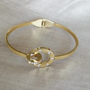 Edblad armband  - Edblad armband i modell Ida Bangle Gold ordinarie pris:399 kr. Endast använts några gånger.   DIAMETER STOR RING 20 MM, LITEN RING 12 MM, STORLEK SKENA 3X2 MM. INNERSTORLEK S 59X44 MM, L 63X48 MM, ÖPPNINGSBART. KUBISK ZIRKON, BLANK 14K GULDPLÄTERING PÅ RO