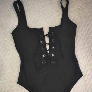  - Svart baddräkt, strl M, helt oanvänd. Från Vero Moda  snygg urringning i ryggen samt smickrande snörning framtill som även gör det möjligt att justera baddräktens passform utifrån önskemål.