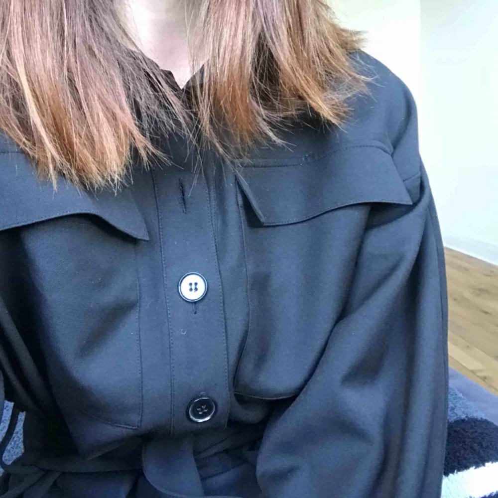 Ny och oanvänd svart skjortklänning från H&M! Knappar upptill och bälte i midjan, lite ballongärm! Storlek 34 men tror absolut den funkar på en 36:a med🌹 nypris 599kr. Klänningar.