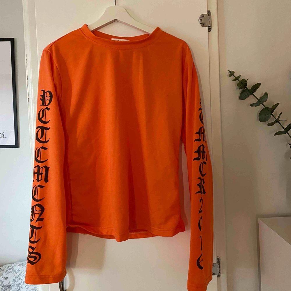 Superfin orange tröja med svarta textdetaljer, säljes då den aldrig kommer till användning längre 🥺 Betalas med swish och köparen står för frakten 🌸. Toppar.