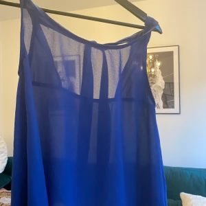 Blå blus  - Blå blus med fin knytdetalj i ryggen! Märke okänt, men är knappt använd! 