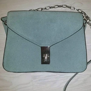 Väska mango - Axelremsväska i en fin grön färg i mocka från Mango. 