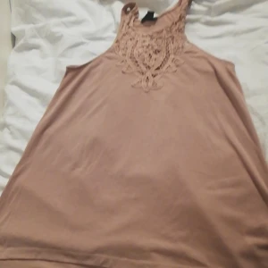 Tröja  - Ett rosa linne med detalj vid halsen. 