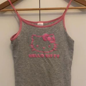 Hello Kitty linne top  - Jättefint linne med hello Kitty på! Köpt secondhand och behöver tyvärr säljas pga flytt. , det är nog använt av den förra ägaren  men inget som märks. Den har ingen storlek men skulle säga att den passar xs-m , då den är stretchig! Frakt tillkommer. Tveka inte att skriva om ni har frågor eller vill ha fler bilder! ;)