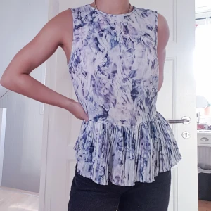 Fin mönstrad blus - En jättefin blå, vit, lila mönstrad blus. Dragkedja bak. Sorlek 34 men sitter som den glr på bilden på mig som är storlek 36. 