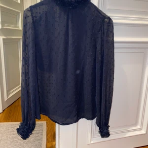 Blus med blommor från Zara - Marinblå blus från Zara med blommor vid kragen och muddar vid handlederna. Aldrig använd. 