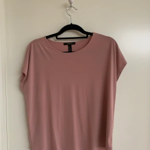 T-shirt strl M - Rosa lite ”glansig” t-shirt från forever21. Skön och lite luftig modell. strl M men passar både S och L lite beroende på vilken passform man vill ha. Frakt tillkommer