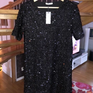 Glittrig klänning  - Perfekt inför nyår eller liknande. Svart glittrig paljettklänning från Vila storlek M, helt oanvänd med prislapp kvar då den inte passar i storleken. Ordinarie pris 400 kr, säljes för 50 kr.