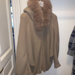 Tröja/jacka i ull - Underbar tröja/jacka med luva och pälskrage. Tröjan är stickad i angora/mohair och försluts med dragkedja. Inköpt i Nice för ett par år sedan. Rymlig modell, pssar sannolikt XS-M. 