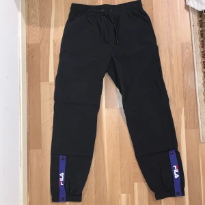 Vindbyxor från Fila  - Svarta vindbyxor från Fila. Jättebra skick men tyvärr för små för mig. Hör av dig om du har någon fråga :) 