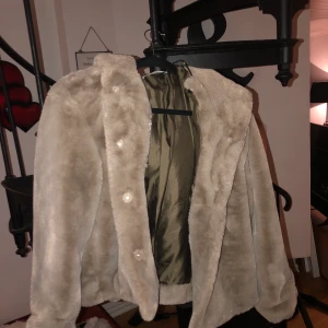Fuskpäls Jacka - Mycket fin jacka i fuskpäls med luva i brunbeige färg. Köpt här på plick men typ aldrig använd! ✨