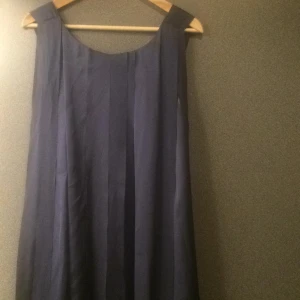  - Underbar klänning i satinmaterial i olika lager som skapar ett fantastiskt fall. Klänningen är från Tiger of sweeden, köpt förra vintern och använd endast ett fåtal gånger, klänningen är i felfritt skick. Den är inte figurnära utan passar kroppar från storlek 36-40