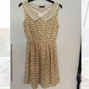  - Söt krämfärgad, kaddmönstrad klänning med Peter pan-krage.  Oanvänd med prislappen kvar.  