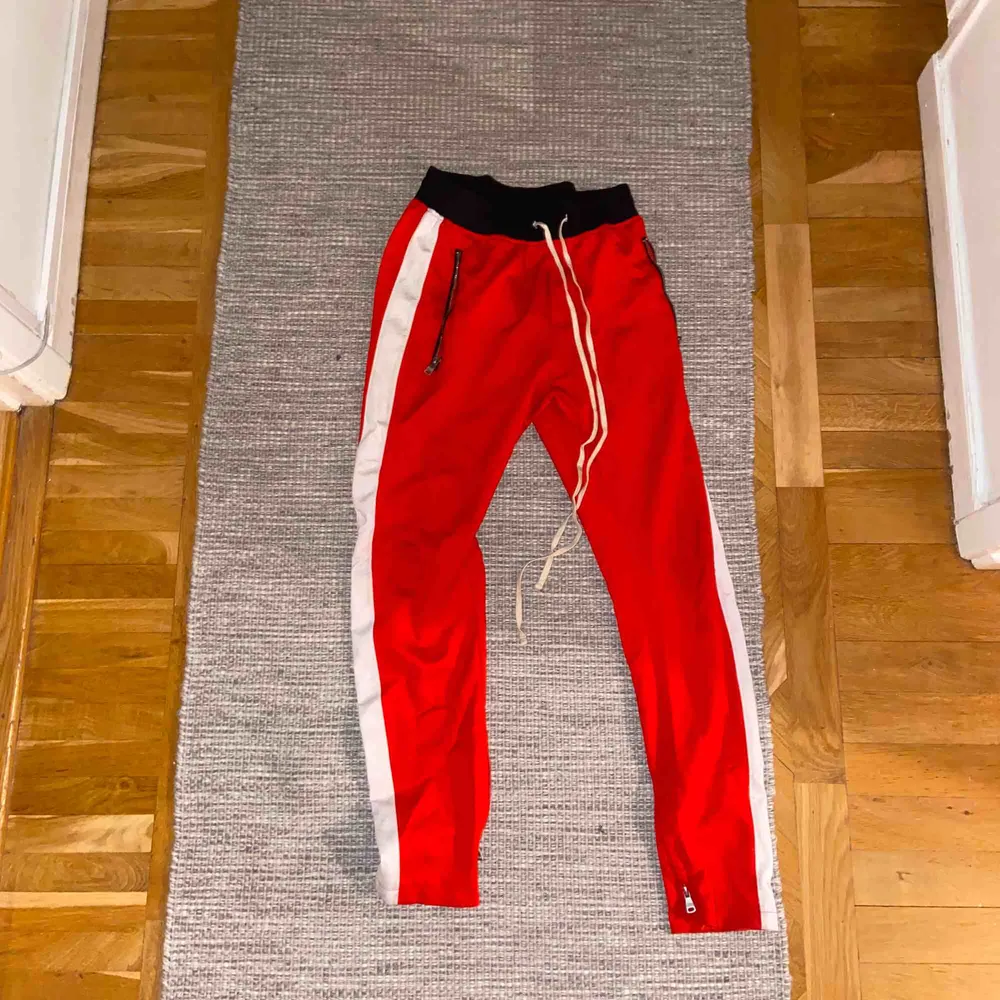 Skitfeta röda trackpants i storlek 32, har en slim-fit med dragkedjor längsmed anklarna. Perfekt för en skön och mysig outfit. . Jeans & Byxor.