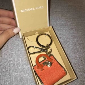  - BUD PÅ TRADERA! Skick: Ny. Sitter fortfarande fast i sin original kartong.  Märke: Michael Kors. Riktigt fin nyckelring/charm från Michael Kors tangerine MK Hamilton bag miniatyr i gulddetaljer. Är en utmärkt present!
