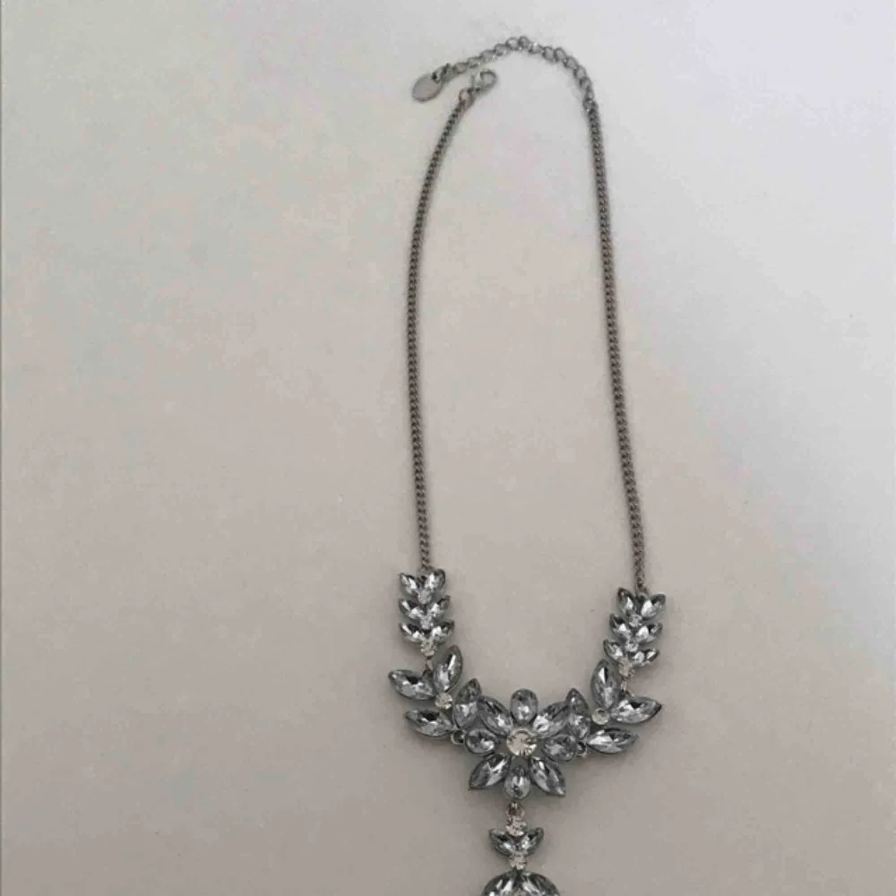 Vilket bling bling halsband! Jätte fint silvrigt halsband med glittriga stenar i form av en blomma med blad runtomkring. Använd max 1 gång, nyskick! Normal längd på kedjan. Verkligen jätte fint! . Accessoarer.