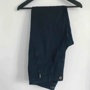  - Marinblå kostymbyxor i en smal modell! Dragkedja vid anklarna. Passar strl S