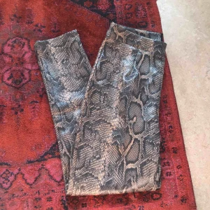  - Byxor i ormskinnsmönster från boohoo. Helt oanvända pga för stor storlek. 155kr inklusive frakt.