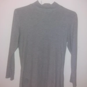 - Grå tröja med långa armar o en liten krage uppe vid halsen 