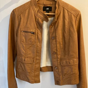 Brun ”skinnjacka” - Fin, lite kortare jacka i fejk-skinn 🔥 Passar perfekt på sommaren när man inte vill ha en så varm jacka ☀️ Många fina detaljer, och i jättefint skick ✨ Köpt för ett par år sedan! ❣️ Köparen står för frakt, hör av er vid frågor/fler bilder 😊