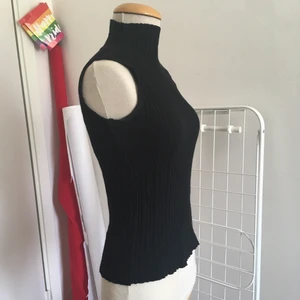 Svart polotröja S/M - Stilren polotröja från Holly Bracken, med lettuce hem detalj runt halsen och höfterna.