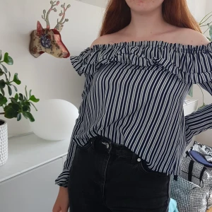 Off-shoulder tröja - En långärmad off-shoulder tröja med vita och mörkblå ränder. + frakt