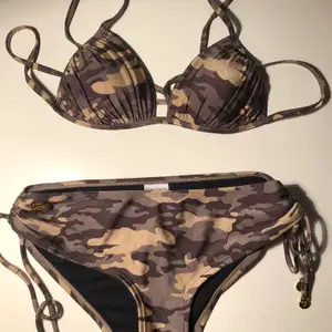 Bikini i militärmönster med snygga gulddetaljer från Chiara Forti. Köptes inför en utlandsresa och använde en gång, efter det har den ej kommit till användning. Toppen är i strl S och underdelen i M. 
