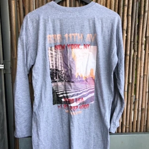 Långärmad klänning med tryck - En grå långärmad chillad klänning från missguided. Storlek 36 och använd 1 gång. Trycket är på ryggen och klänningen går till knäna på mig ( 166cm lång ) super snygg att bara dra på sig. 