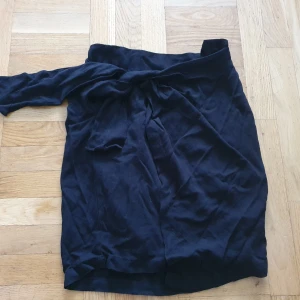 Soaked kjol svart strl XS - Svart knälång kjol. Omlott knytning fram, men dragkedja bak. Oanvänd. FRAKT INGÅR EJ